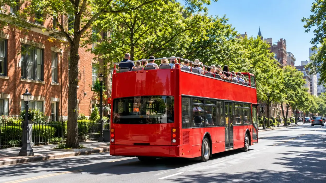 Un bus de tourisme rouge à impériale découvert sur une rue ensoleillée de la ville