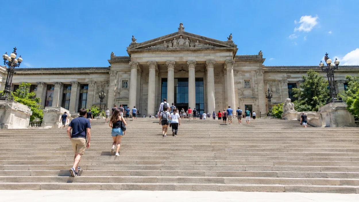 Una amplia escalinata de piedra de museo con personas subiendo en un día soleado