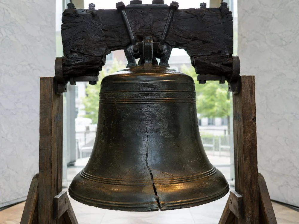 Die Freiheitsglocke, die von ihrem hölzernen Joch hängt, im Tageslicht beleuchtet